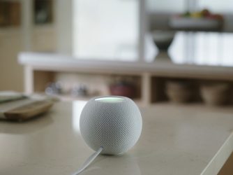 HomePod mini postavený na konferenčním stolku v obývacím pokoji